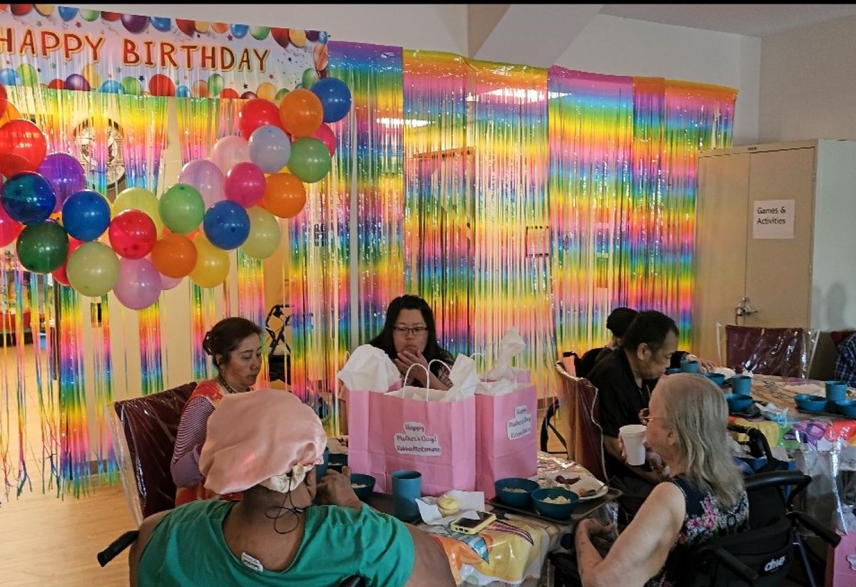 Residents celebrating a birthday with balloons and gift bags